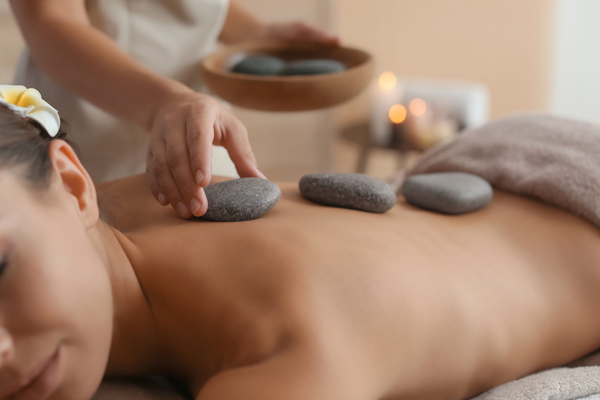 Therapist placing warm basalt stones along the spine during a hot stone session